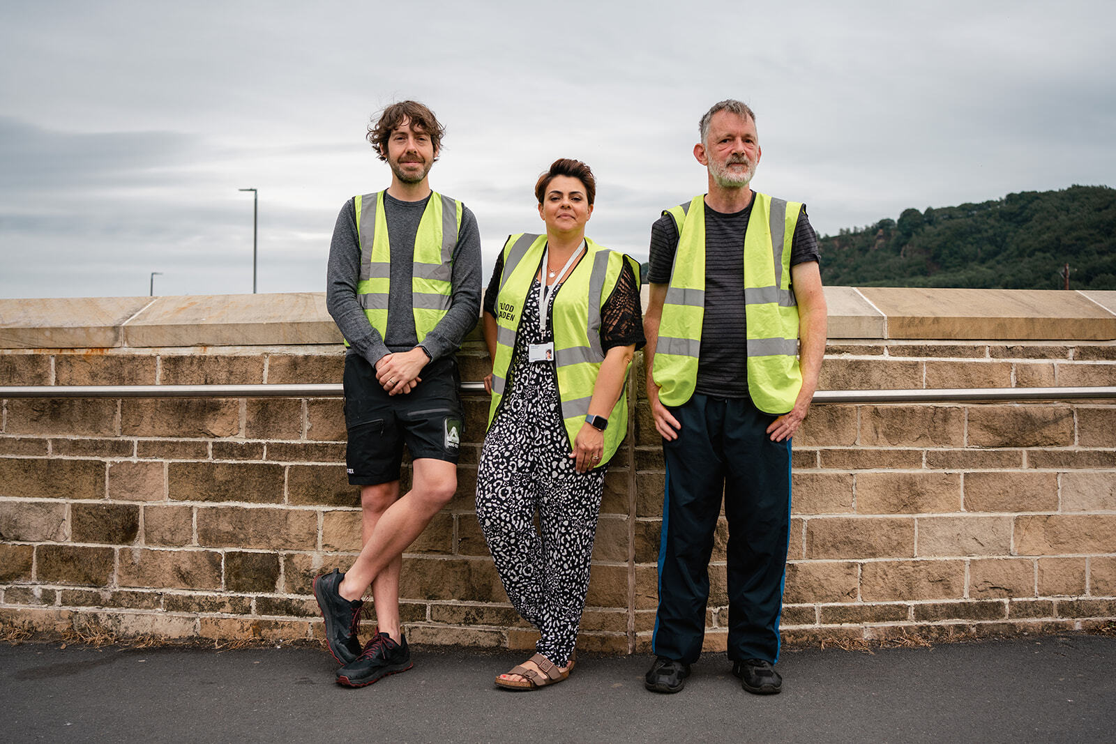 Three of Calderdale flood wardens in high- vis jackets on bridge in borough