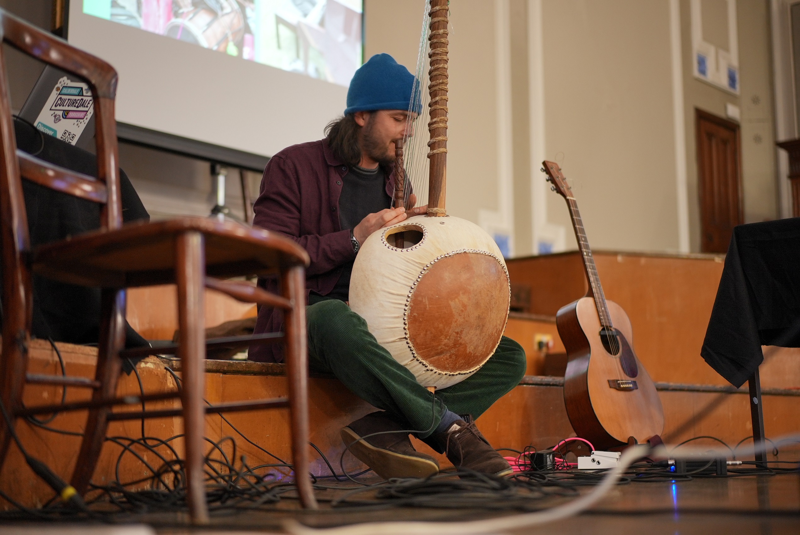 Man performs on stage with a traditional instrument