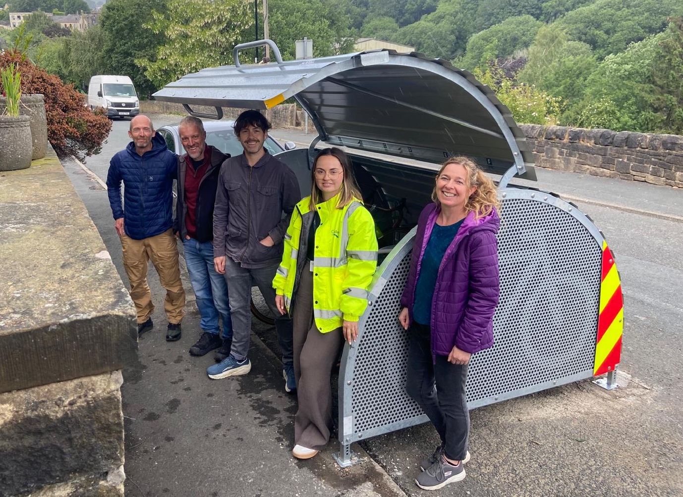 Councillors and council staff next to new cycle hangar on street in Mytholmroyd