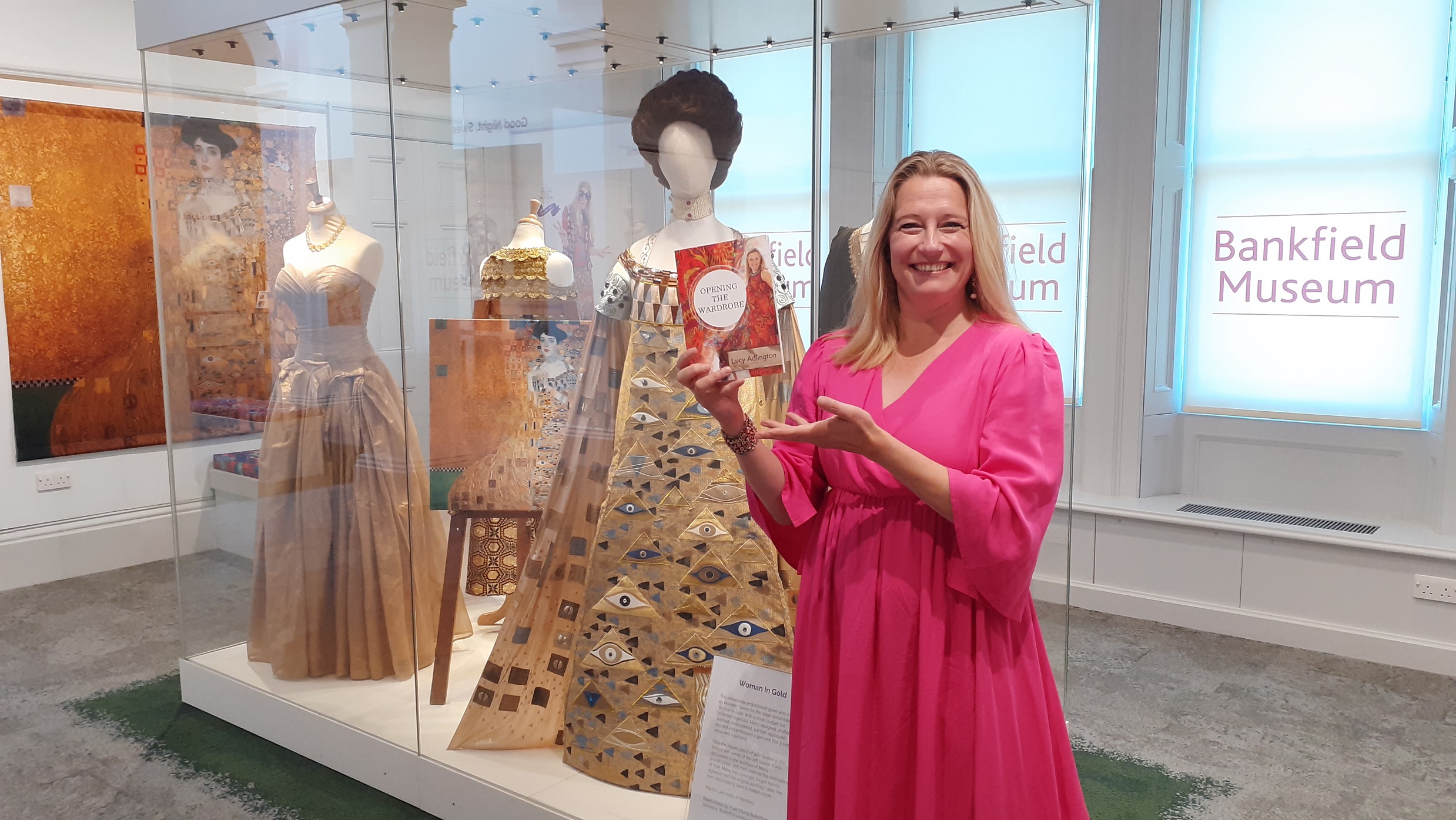Lucy Adlington at Bankfield Museum in front of glass case containing dresses