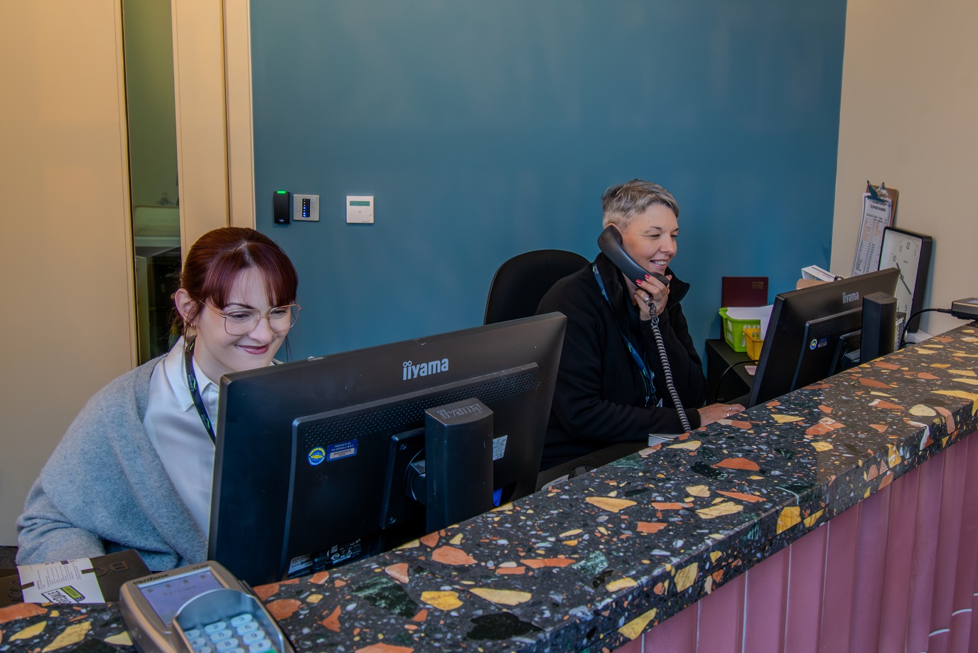 Two members of staff working at computers in new theatre box office