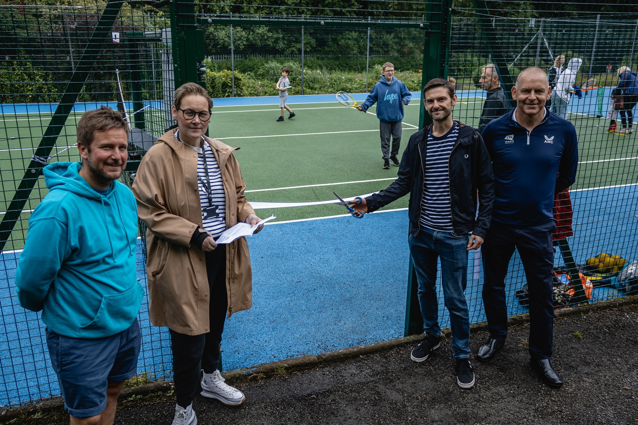 Group gathered in front of newly refurbished tennis courts at Crow Wood Park