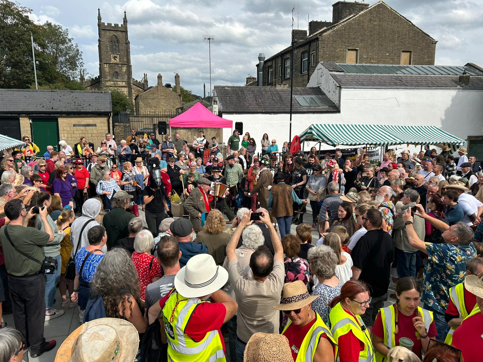 A crowd of people gathered watching Rushbearing in Sowerby Bridge Square
