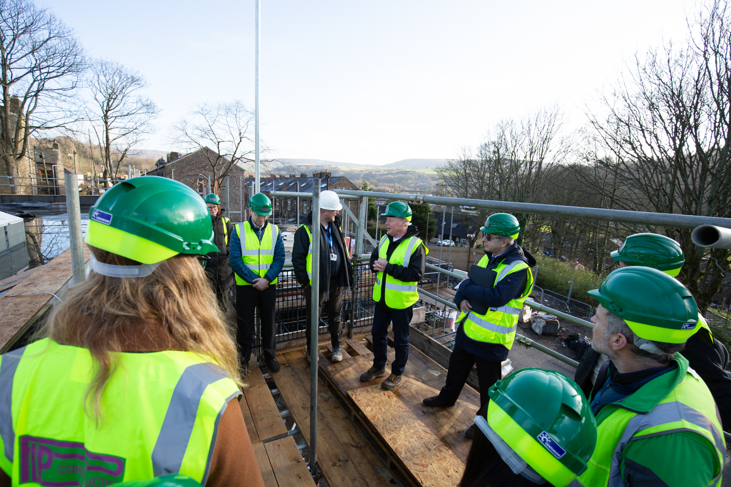 People in hi-vis on the roof of Ferney Lee Enterprise Centre in Todmorden, looking at environmental features
