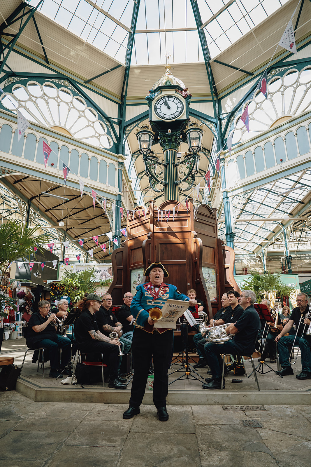 Town Crier and brass band by restored historic clock in Halifax Borough Market